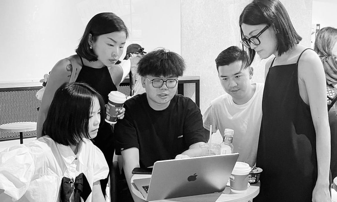 Sense By Mei team engaged in a vibrant discussion, embodying the fusion of cultures and the meticulous crafting of elegance in their fashion creations.