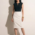 A professional woman modeling an elegant black and white color-block sheath dress, featuring a sleeveless black bodice with metallic hardware and a tailored white pencil skirt for a sophisticated executive look.