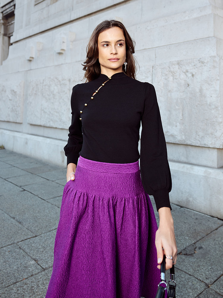 Fashion-forward individual posing against a neutral backdrop, showcasing a modern cheongsam dress in magenta and mauve with a sophisticated silhouette.