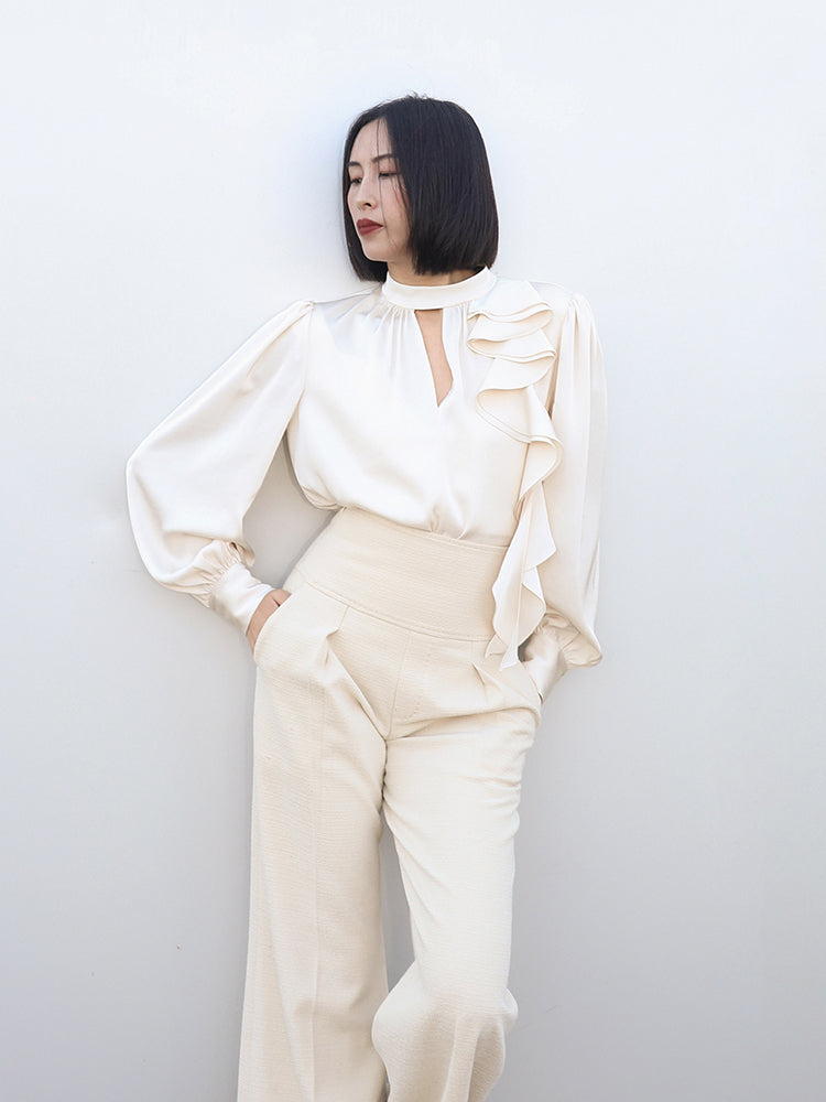 Profile view of SENSE by Mei's white satin blouse, highlighting the ruffled neckline and shoulder pleats.
