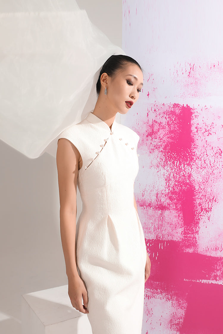 Elegant Tulip Vase-Shaped Cheongsam Dress in white, with the model's side profile against a pink wall, highlighting the unique vase-shaped waist and luxurious pearl buttons.