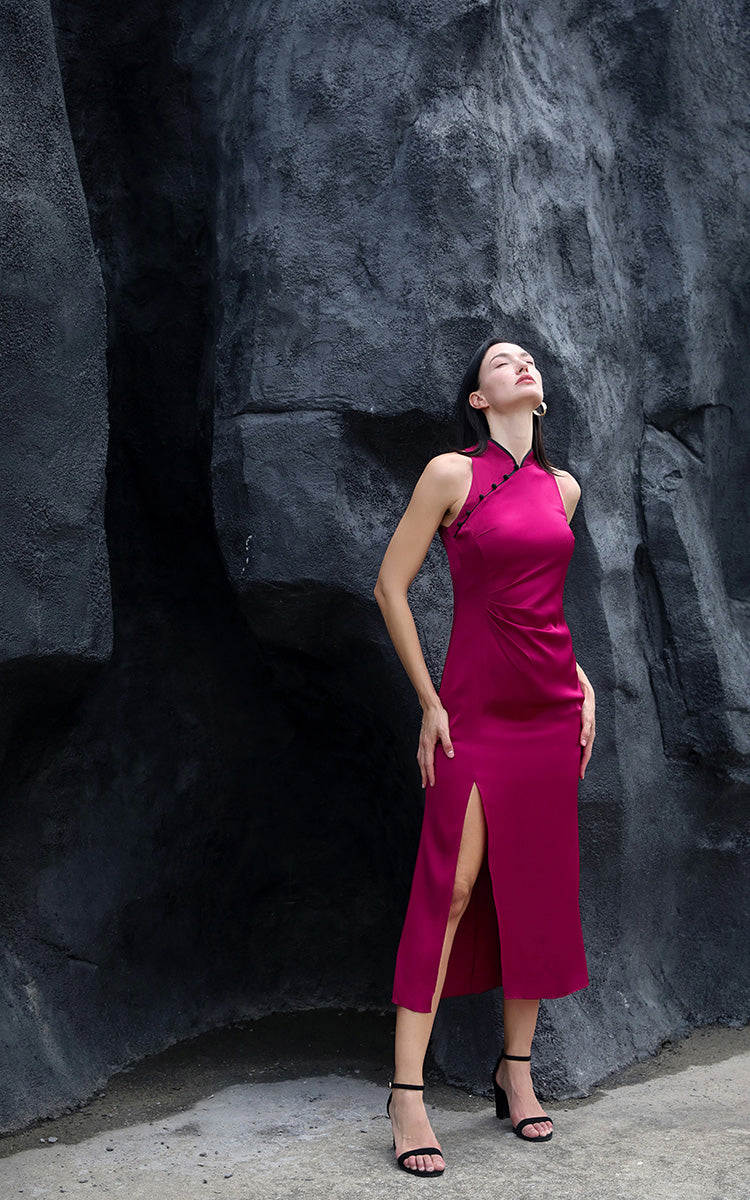 Model in luxurious soft silk Cheongsam dress in dragon fruit pink, with head tilted back and eyes closed, set against a rocky backdrop, highlighting the pearl-like sheen of the 18MM satin silk.