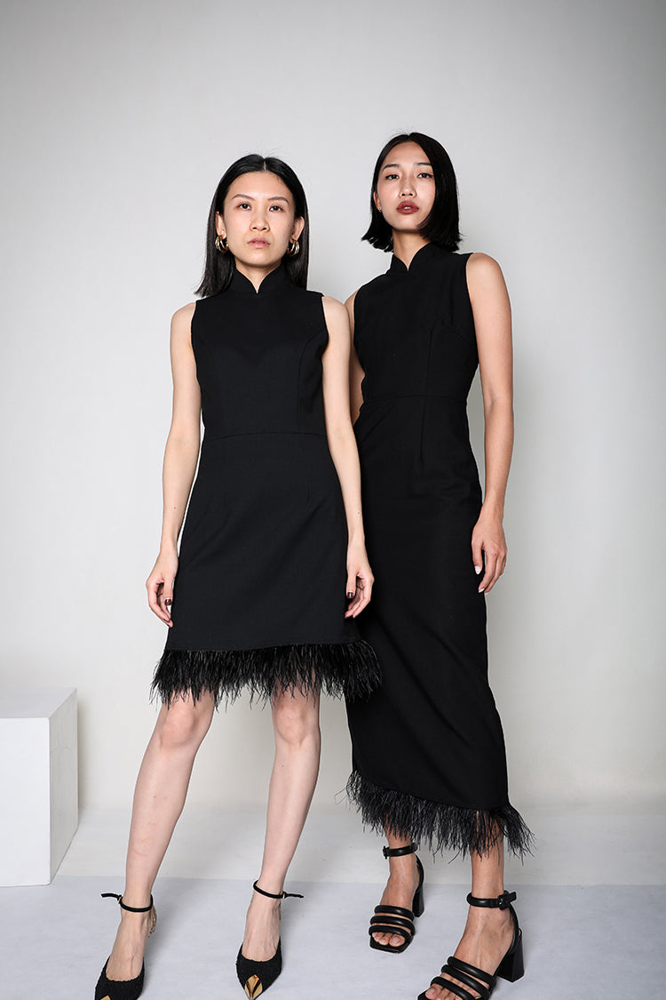 Two models posing side by side, one in a long black Cheongsam dress with ostrich feather details and the other in a short version, both exemplifying modern sophistication and elegance.