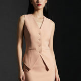 A professional woman wearing a sophisticated apricot-colored tailored vest, featuring a deep V-neckline and a unique pointed hem for an elegant executive office look.