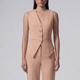 A professional woman wearing a sophisticated apricot-colored tailored vest, featuring a deep V-neckline and a unique pointed hem for an elegant executive office look.