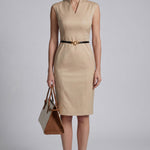 A professional woman wearing a sophisticated beige sleeveless sheath dress, featuring an elegant mandarin collar with a V-neckline and a slim black belt for a polished executive office look.