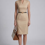 A professional woman wearing a sophisticated beige sleeveless sheath dress, featuring an elegant mandarin collar with a V-neckline and a slim black belt for a polished executive office look.