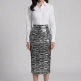 A woman wearing a glamorous high-waisted pencil skirt featuring shimmering silver and black sequins in a stylish zebra print, ideal for an elegant evening party or a night out.