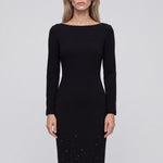 An elegant woman wearing a classic black long-sleeve sheath midi dress featuring a sophisticated boat neckline and a stunning gradient of sparkling rhinestones at the hemline for a refined evening look.