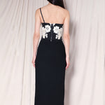 A professional woman wearing a sophisticated high-waisted black pencil skirt, featuring elegant gold-tone mandarin-style buttons and a stylish side slit for a polished executive office look.