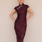 An elegant woman wearing a sophisticated burgundy jacquard modern qipao cheongsam dress featuring a classic mandarin collar, delicate contrast frog closures, cap sleeves, and a tailored sheath silhouette.