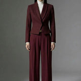 A professional woman wearing a sophisticated burgundy blazer suit with a classic shawl lapel and a white turtleneck, perfect for a high-end executive office look.