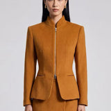 A chic professional Asian woman wearing a luxurious camel wool tailored jacket featuring a sleek stand collar, exposed two-way front zipper, structured shoulders, and an hourglass silhouette paired with a matching skirt.