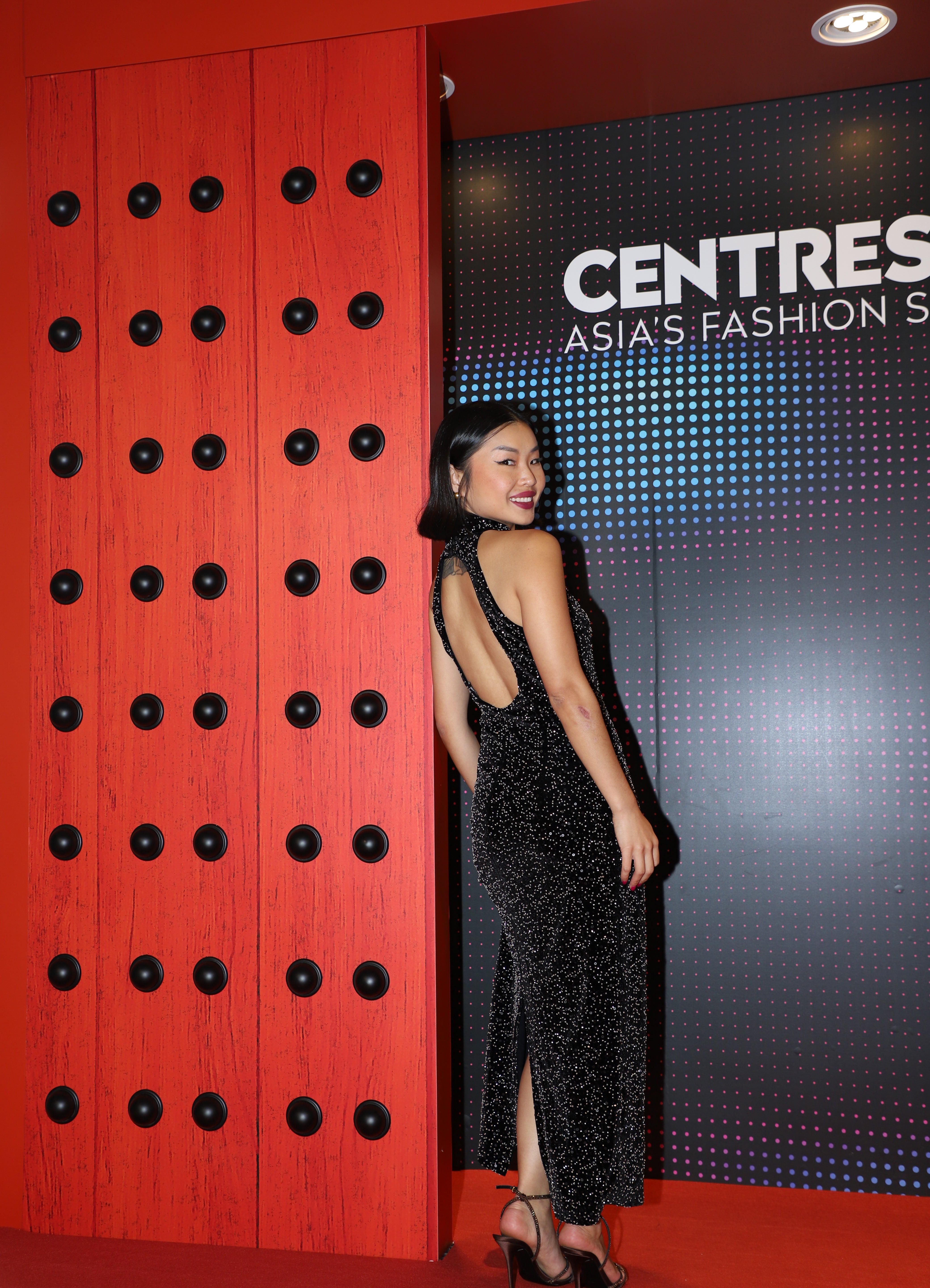 A stunning woman wearing a sophisticated black sequin halter midi dress, featuring a traditional mandarin collar and a shimmering bodycon silhouette, perfect for a modern oriental-inspired evening party look.