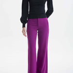 A professional woman wearing sophisticated black high-waisted straight-leg trousers, featuring a tailored silhouette with creased front details for a polished executive office look.