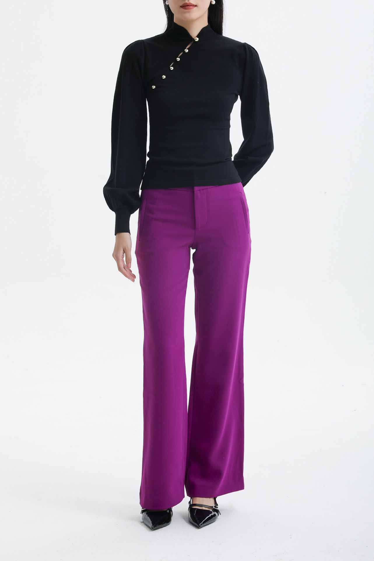 A professional woman wearing sophisticated black high-waisted straight-leg trousers, featuring a tailored silhouette with creased front details for a polished executive office look.
