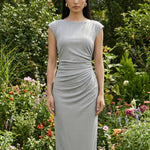 Two professional women modeling elegant sky blue and light grey sheath dresses, featuring a sophisticated boat neck, cap sleeves, and slimming side ruched details for a polished executive look.