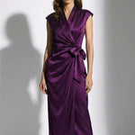A professional woman modeling an elegant deep purple satin wrap midi dress, featuring a sophisticated surplice V-neck, cap sleeves, and a chic side bow tie for a quiet luxury evening or office look.