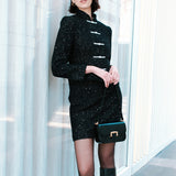 A chic woman wearing a luxurious black sparkle tweed tailored jacket featuring an authentic stand cheongsam collar, elegant horizontal pearl bar closures, and a flattering hourglass waistline.