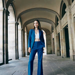 A professional woman wearing sophisticated royal blue high-waisted wide-leg trousers, featuring a tailored loose-fit silhouette for a modern and vibrant executive office look.