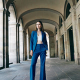 A professional woman wearing sophisticated royal blue high-waisted wide-leg trousers, featuring a tailored loose-fit silhouette for a modern and vibrant executive office look.