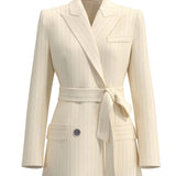 A professional woman wearing a sophisticated cream pinstripe blazer, featuring a double-breasted front with a chic waist-tie belt and notched lapels for a polished old money office look.
