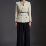 A professional woman wearing a sophisticated cream white tweed skirt suit, featuring a double-breasted blazer with gold buttons, a slim black belt, and an elegant polka dot pussy bow tie for a polished French chic office look.