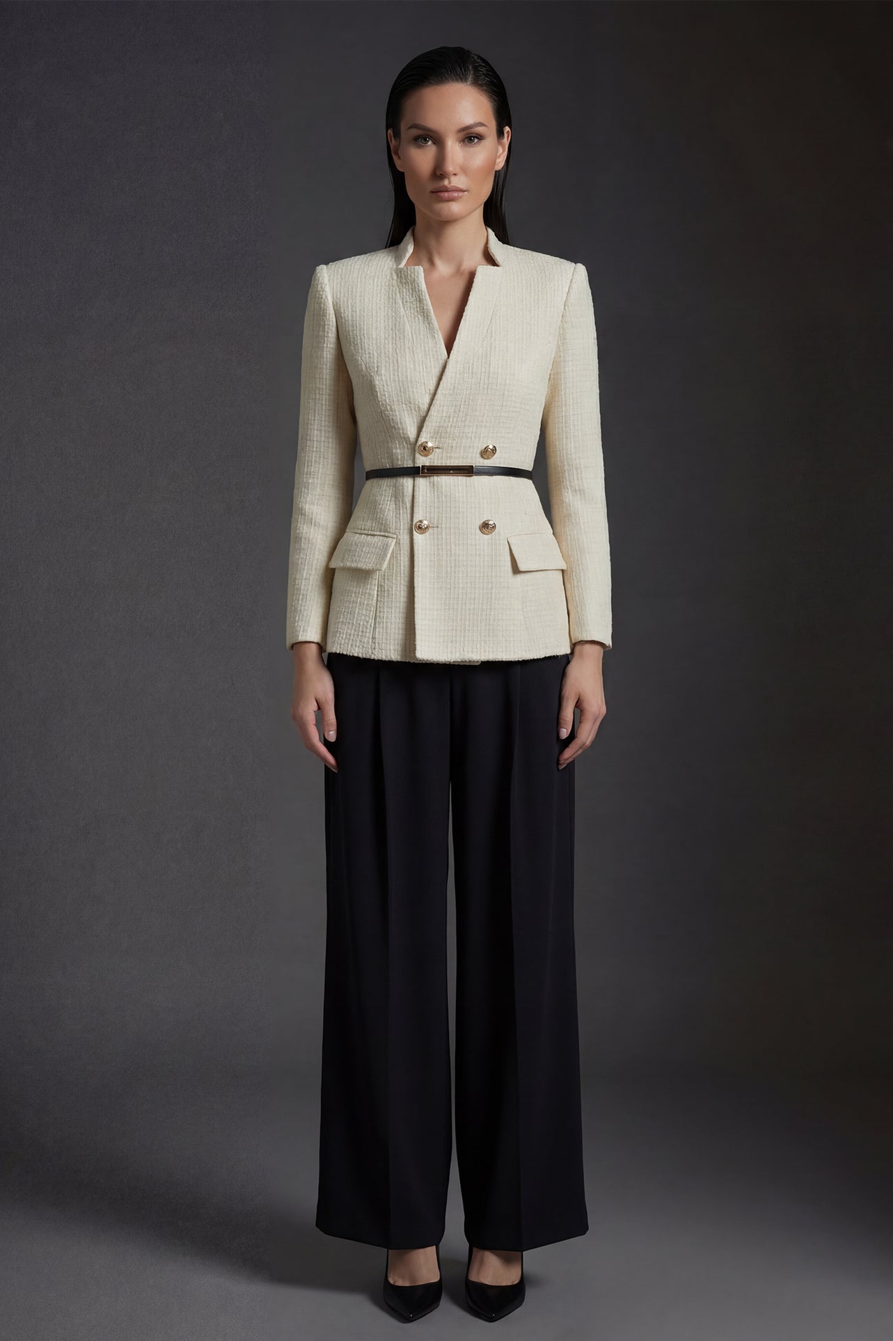 A professional woman wearing a sophisticated cream white tweed skirt suit, featuring a double-breasted blazer with gold buttons, a slim black belt, and an elegant polka dot pussy bow tie for a polished French chic office look.