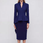 A professional woman wearing a classic navy blue high-waisted tailored pencil midi skirt with subtle front darts, neatly paired with a crisp white long-sleeve button-down shirt for an elegant corporate look.
