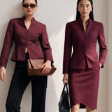A professional Asian woman wearing glasses and an elegant deep burgundy tailored blazer featuring a sophisticated stand collar with a split V-neckline, structured shoulders, and a clean minimalist front.