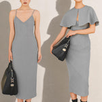 A stylish woman walking on a city street wearing an elegant light grey sheath midi dress with a sophisticated capelet sleeve design, round neckline, and side slit, carrying a black leather handbag.