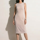 A professional woman modeling an elegant mustard yellow sleeveless sheath dress, featuring a sophisticated crew neckline and a tailored slim fit with princess seams for a polished executive look.