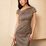 A professional woman wearing a sophisticated taupe grey sheath dress, featuring a chic asymmetric neckline, cap sleeves, and a tailored slim-fit silhouette for an elegant office look.