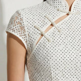 A professional woman modeling an elegant white lace modern qipao dress, featuring an intricate eyelet textured fabric, a sophisticated mandarin collar with a traditional knot button, and slimming cap sleeves.