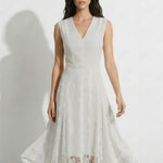 A professional woman modeling an elegant white lace sleeveless dress, featuring a sophisticated V-neckline, a tailored fit-and-flare silhouette, and an intricate hollow-out eyelet texture with a delicate lace trim hem.