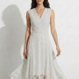 A professional woman modeling an elegant white lace sleeveless dress, featuring a sophisticated V-neckline, a tailored fit-and-flare silhouette, and an intricate hollow-out eyelet texture with a delicate lace trim hem.