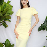 A professional woman wearing a sophisticated pale yellow short-sleeve midi dress, featuring elegant puff sleeves and a slimming ruched waistline for a polished and fresh summer office look.