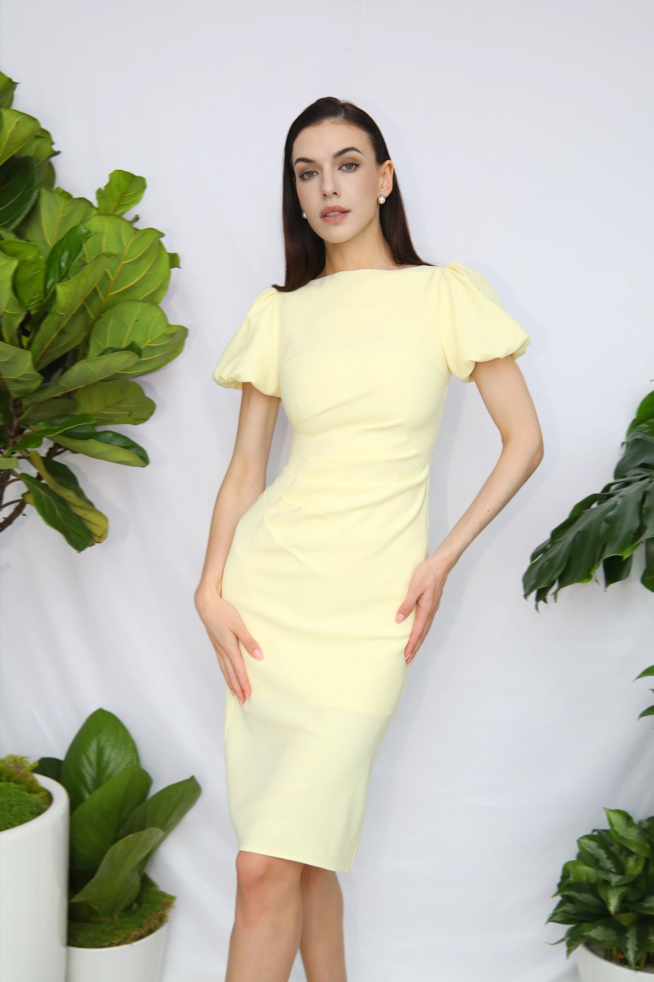 A professional woman wearing a sophisticated pale yellow short-sleeve midi dress, featuring elegant puff sleeves and a slimming ruched waistline for a polished and fresh summer office look.