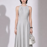 A style comparison of two elegant tailored midi dresses with a flowing high-low hem; the left showcasing a sophisticated light grey dress with a structured collared capelet sleeve, and the right featuring a vibrant purple sleeveless dress with refined pleated neckline and side pockets.