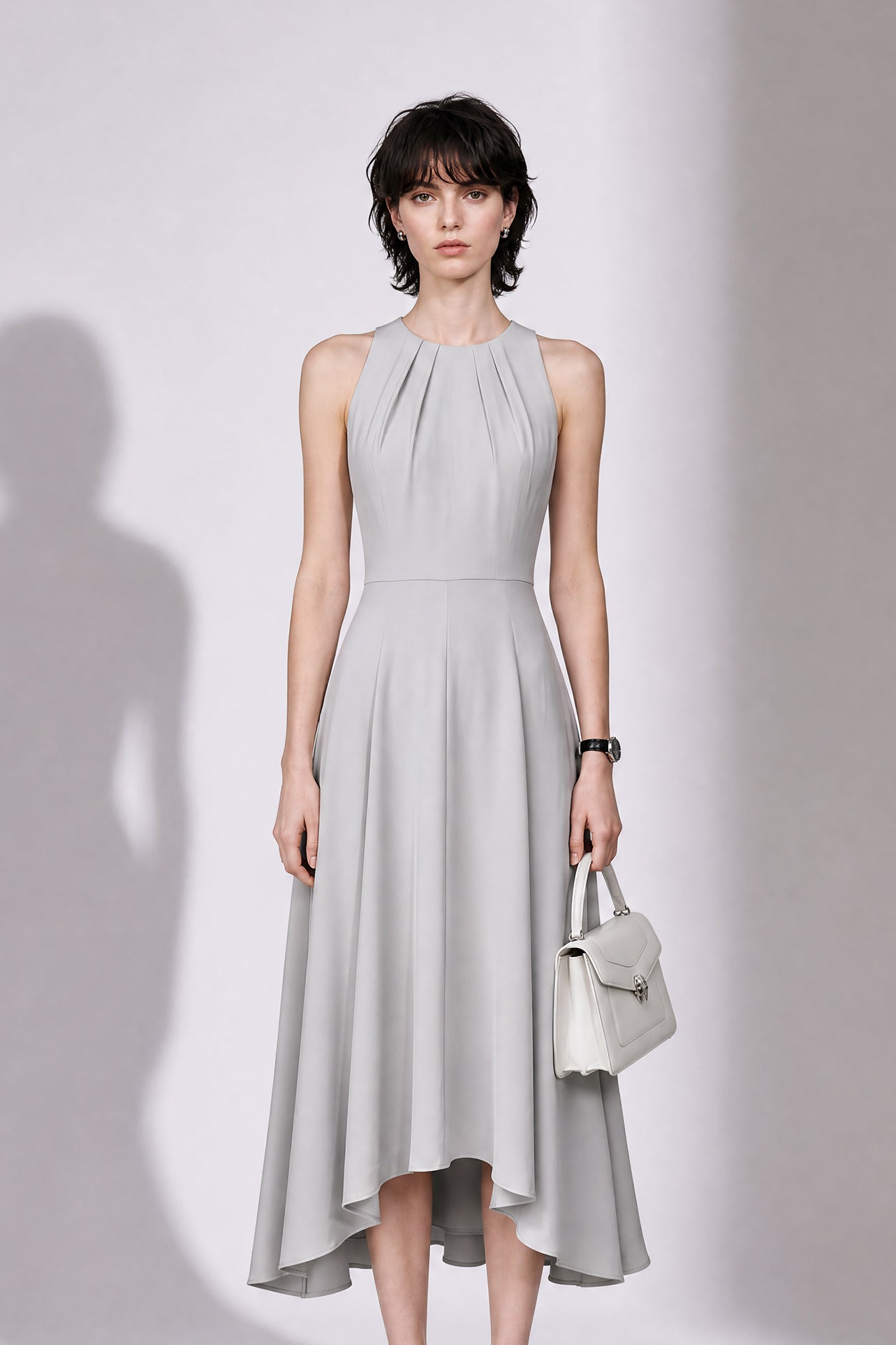 A style comparison of two elegant tailored midi dresses with a flowing high-low hem; the left showcasing a sophisticated light grey dress with a structured collared capelet sleeve, and the right featuring a vibrant purple sleeveless dress with refined pleated neckline and side pockets.