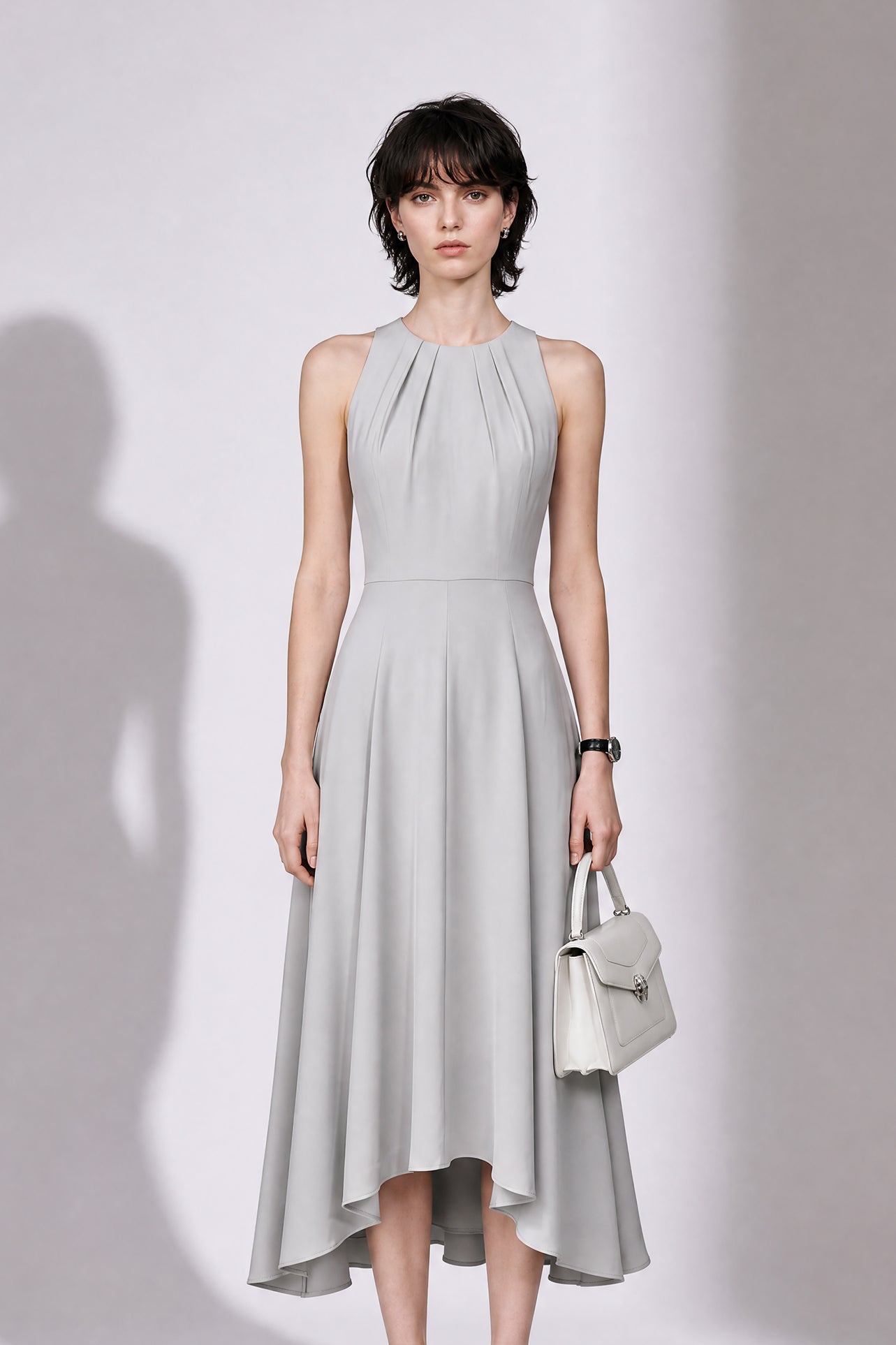 A style comparison of two elegant tailored midi dresses with a flowing high-low hem; the left showcasing a sophisticated light grey dress with a structured collared capelet sleeve, and the right featuring a vibrant purple sleeveless dress with refined pleated neckline and side pockets.