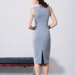 A professional woman wearing a sophisticated light grey pinstripe sleeveless sheath dress, featuring an elegant boat neckline and a tailored slim-fit silhouette for a polished executive look.