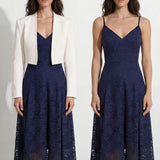 A professional woman modeling an elegant navy blue lace midi dress, featuring delicate V-neck spaghetti straps, a tailored fit-and-flare silhouette, and a beautiful flowing asymmetric handkerchief lace trim hem.