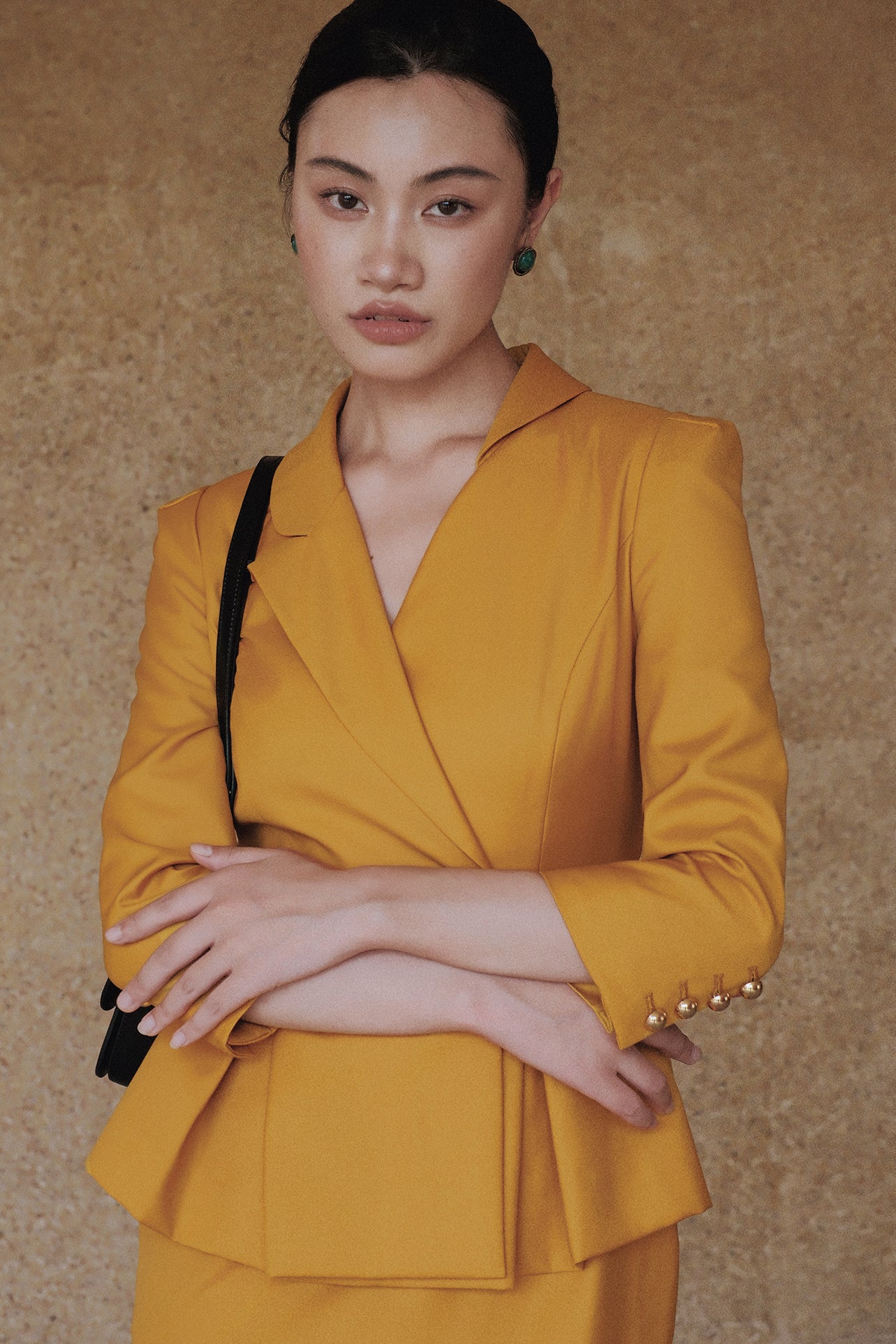 A style comparison of two elegant women's skirt suit sets featuring three-quarter sleeve blazers with single-button closure and pleated peplum hems, paired with matching pencil skirts in mustard yellow and deep teal blue.