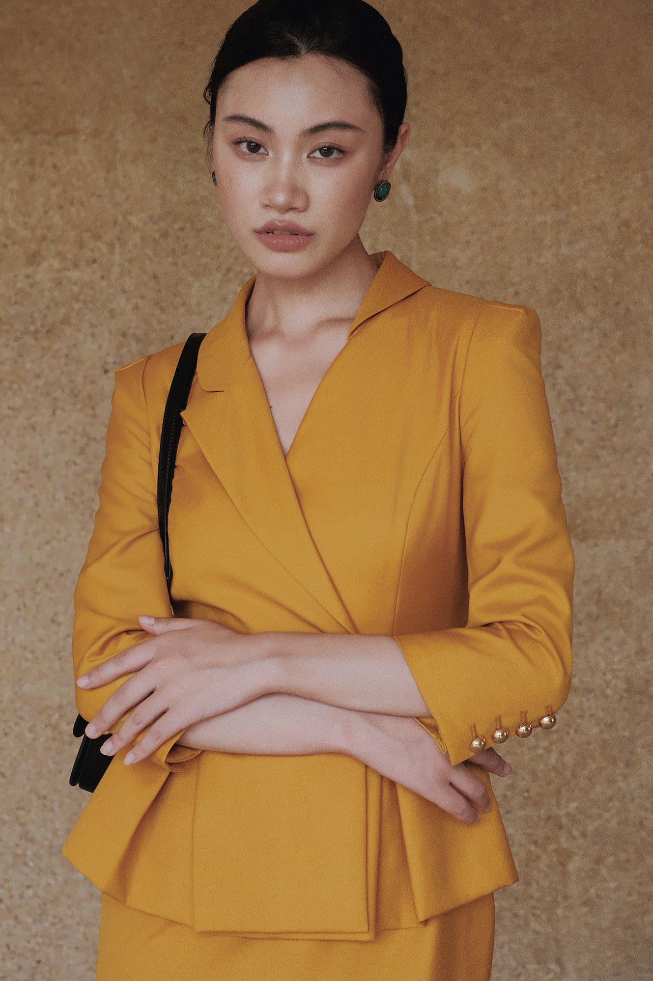 A style comparison of two elegant women's skirt suit sets featuring three-quarter sleeve blazers with single-button closure and pleated peplum hems, paired with matching pencil skirts in mustard yellow and deep teal blue.