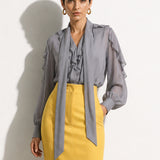 A style comparison of two professional corporate outfits featuring long-sleeve ruffled chiffon blouses with versatile tie-neck scarves; the left styled in purple with white wide-leg trousers, and the right in grey paired with a mustard yellow high-waisted pencil skir