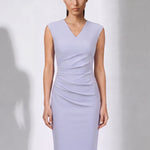 A style comparison of two elegant professional midi dresses with short cap sleeves; the left showcasing a sophisticated teal blue tailored sheath dress with a V-neckline and refined side ruching, and the right featuring the same slimming draping design in a soft pastel lavender lilac color.