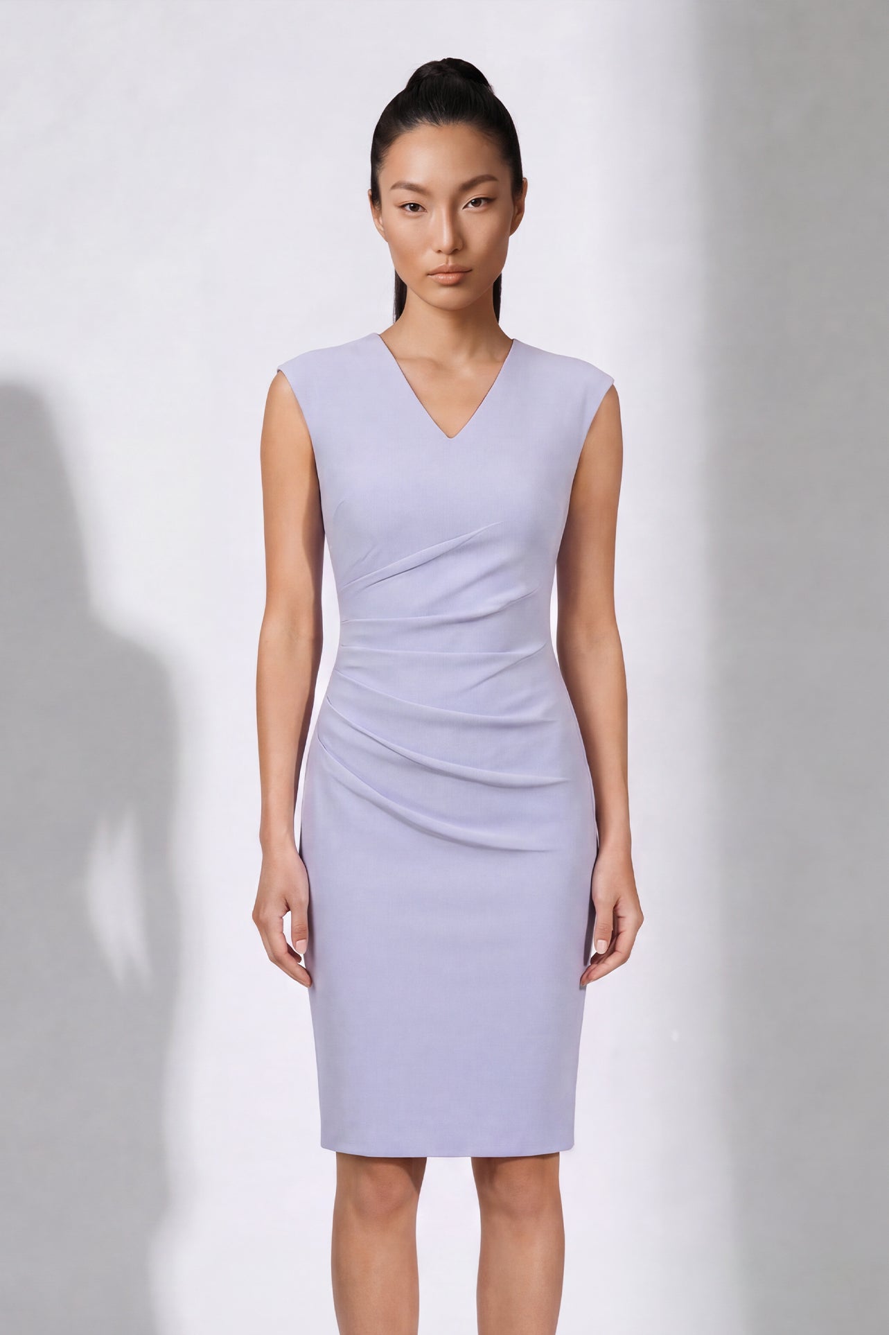 A style comparison of two elegant professional midi dresses with short cap sleeves; the left showcasing a sophisticated teal blue tailored sheath dress with a V-neckline and refined side ruching, and the right featuring the same slimming draping design in a soft pastel lavender lilac color.