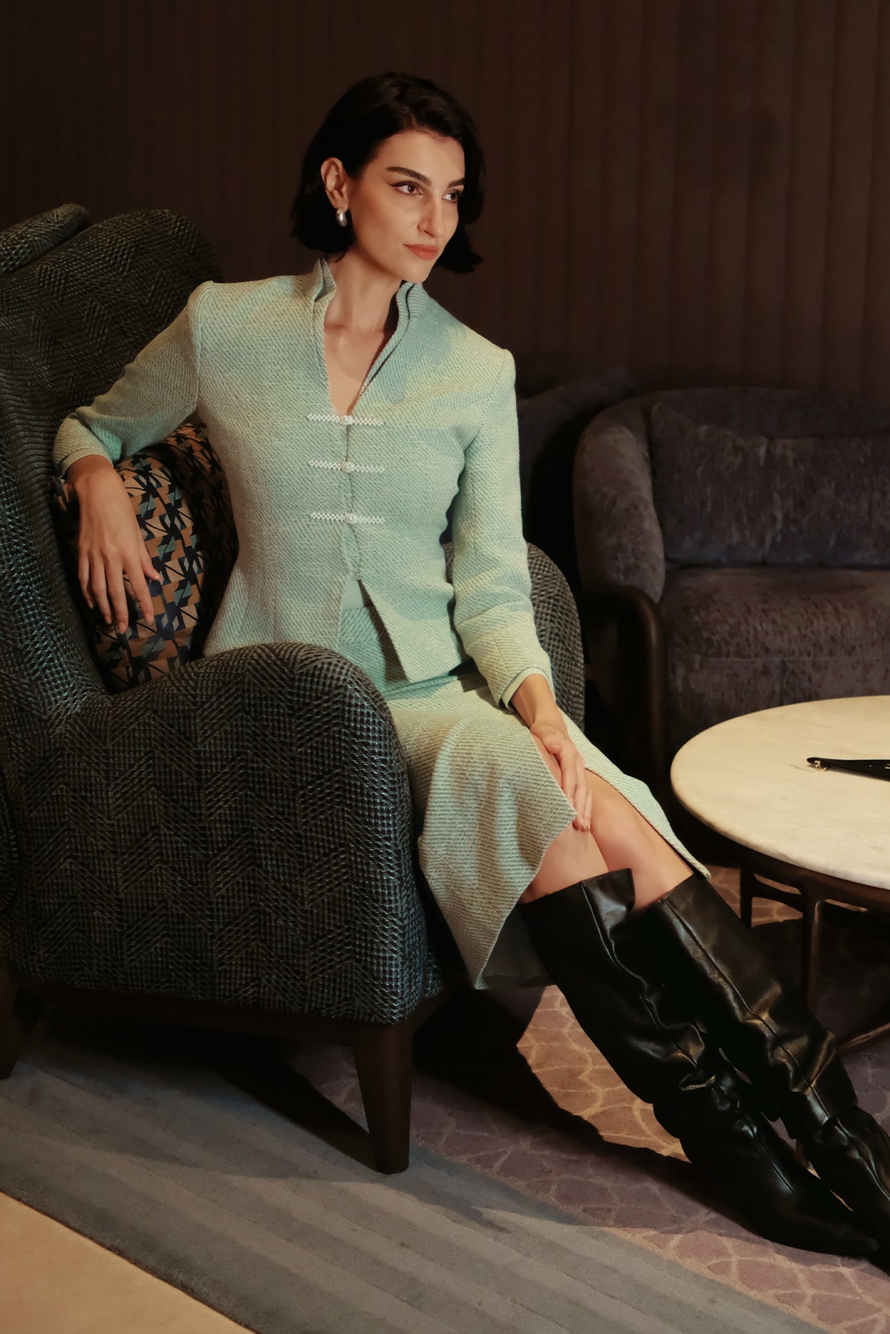 A woman wearing an elegant high-waisted mint green textured pencil midi skirt featuring a clean front waistband and a sophisticated front center slit for a refined corporate chic look.
