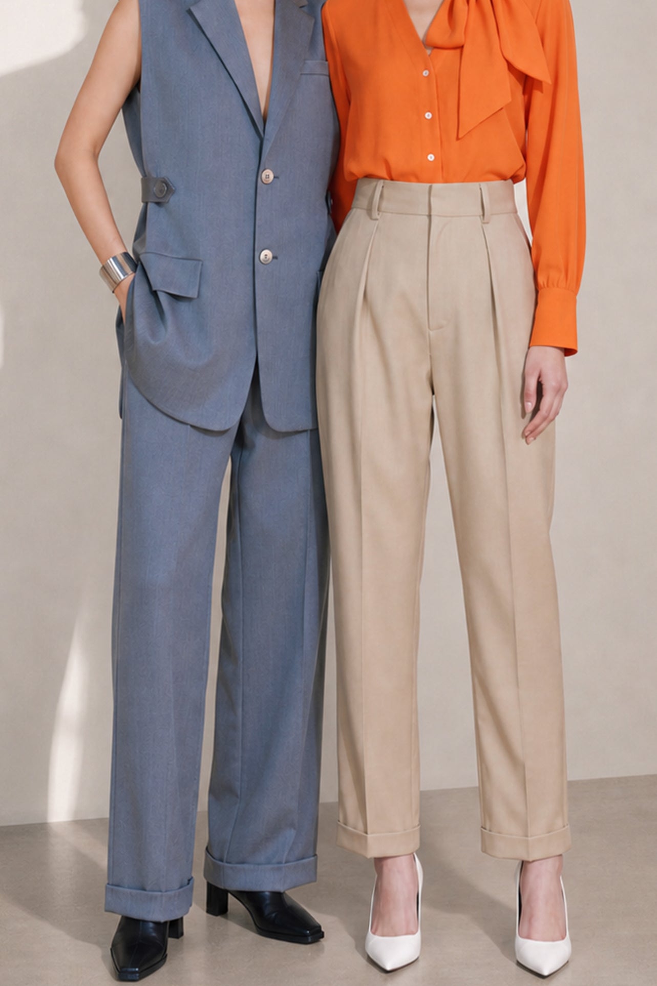A style comparison of two elegant tailored two-piece suit sets featuring longline sleeveless blazer vests with notched lapels and matching cuffed wide-leg trousers; the left shown in slate blue and the right in sophisticated oatmeal beige.